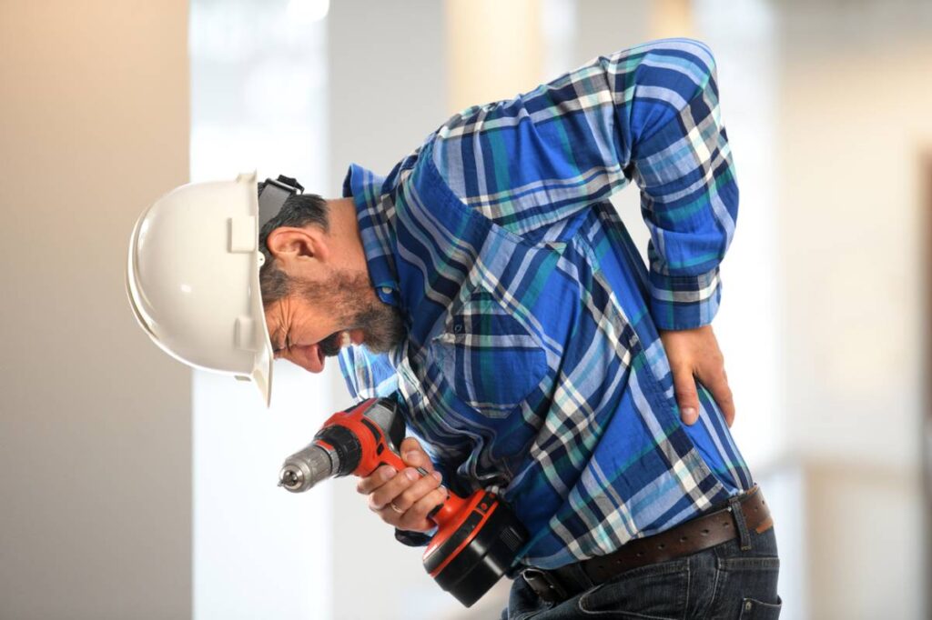 Construction worker experiencing back pain while working.