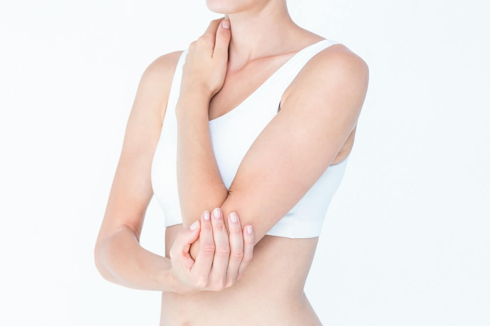 Woman suffering from elbow pain on white background