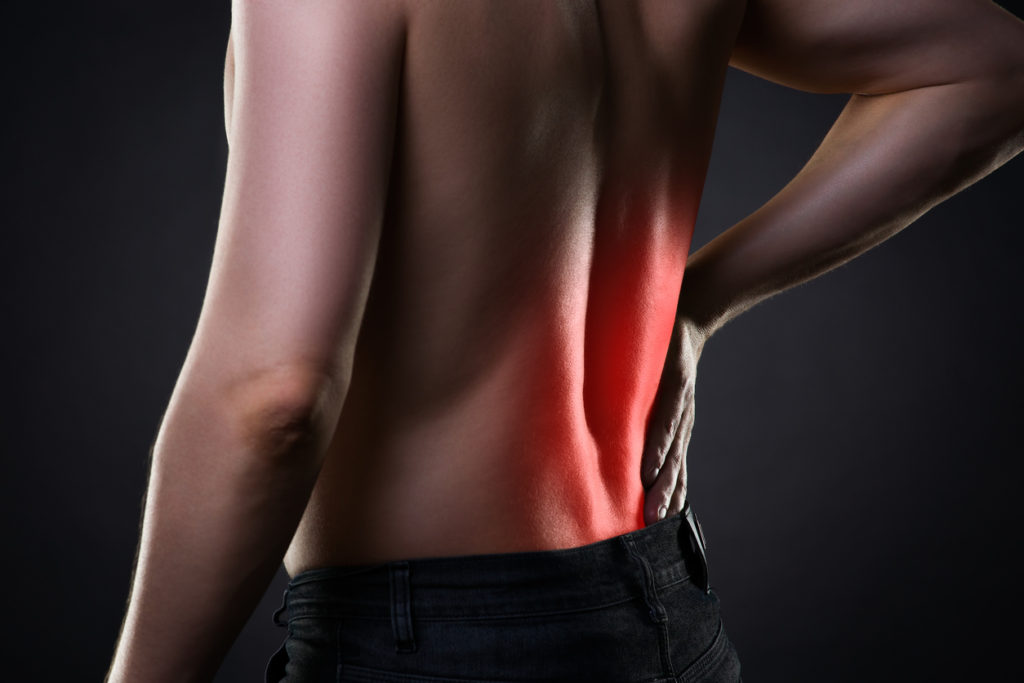 Back pain, kidney inflammation, ache in man's body on black background with red dot