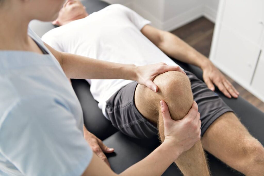 man laying down as doctor grips his knee